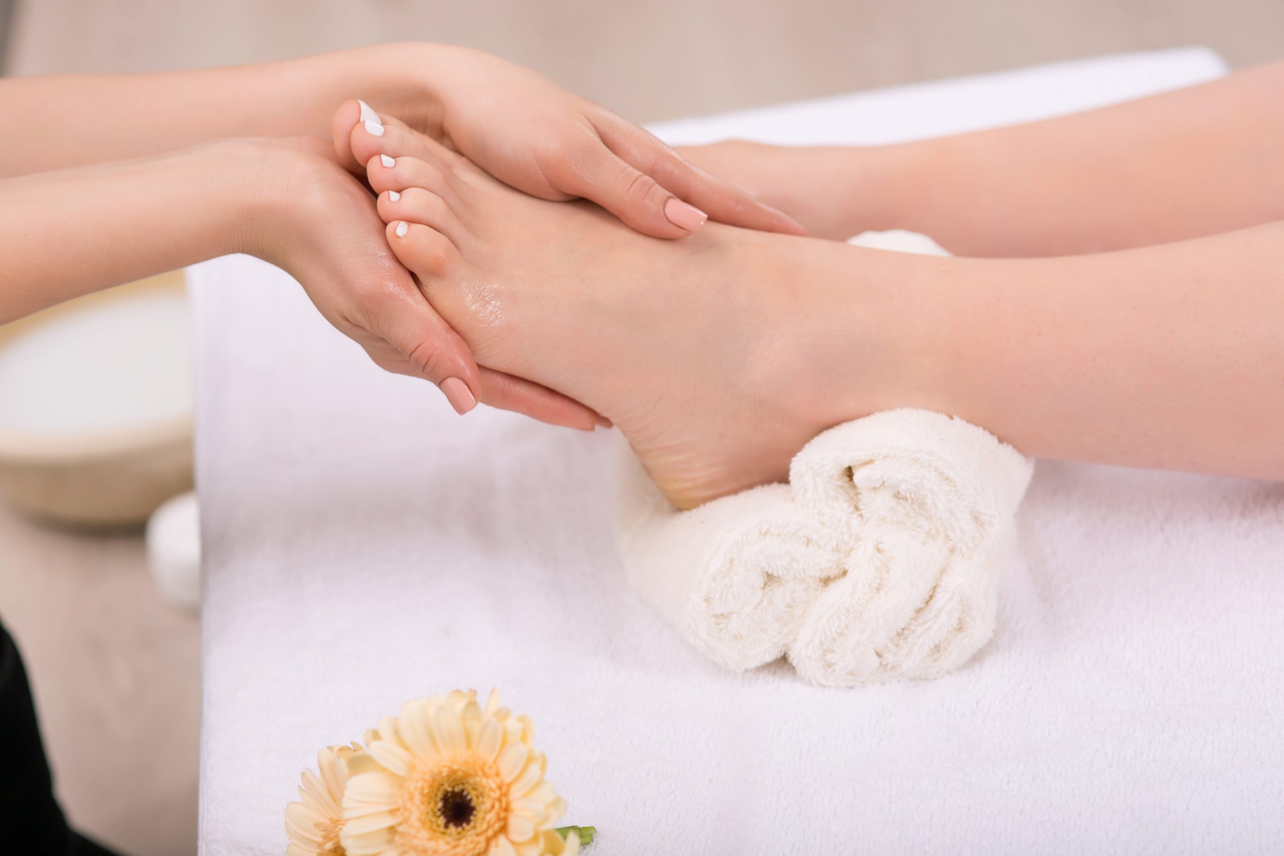 Receive satisfaction. Close up of hands of professional beautician holding feet of the client and massaging them while making  spa procedure