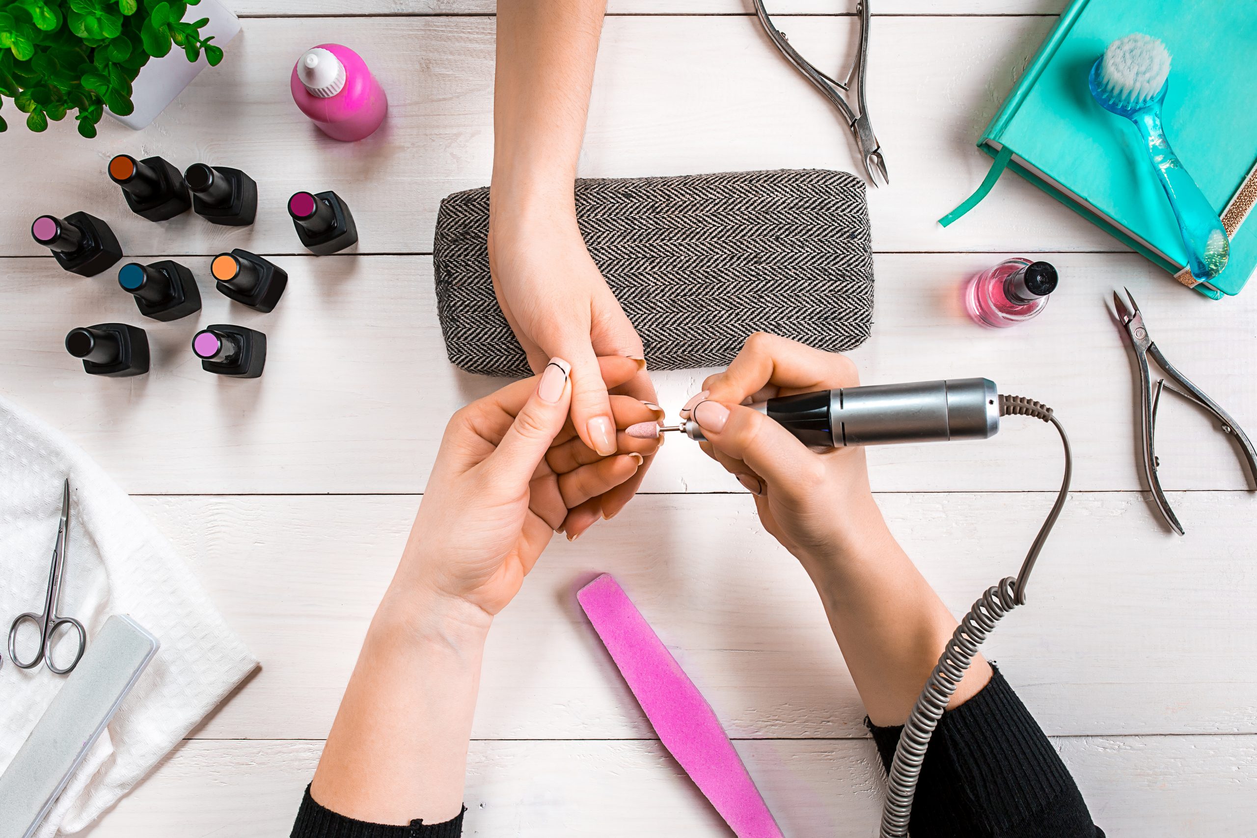 Manicure for the client. Close-up of the hands of a manicurist and client on a wooden background. Nail care. Manicure set and nail polish.