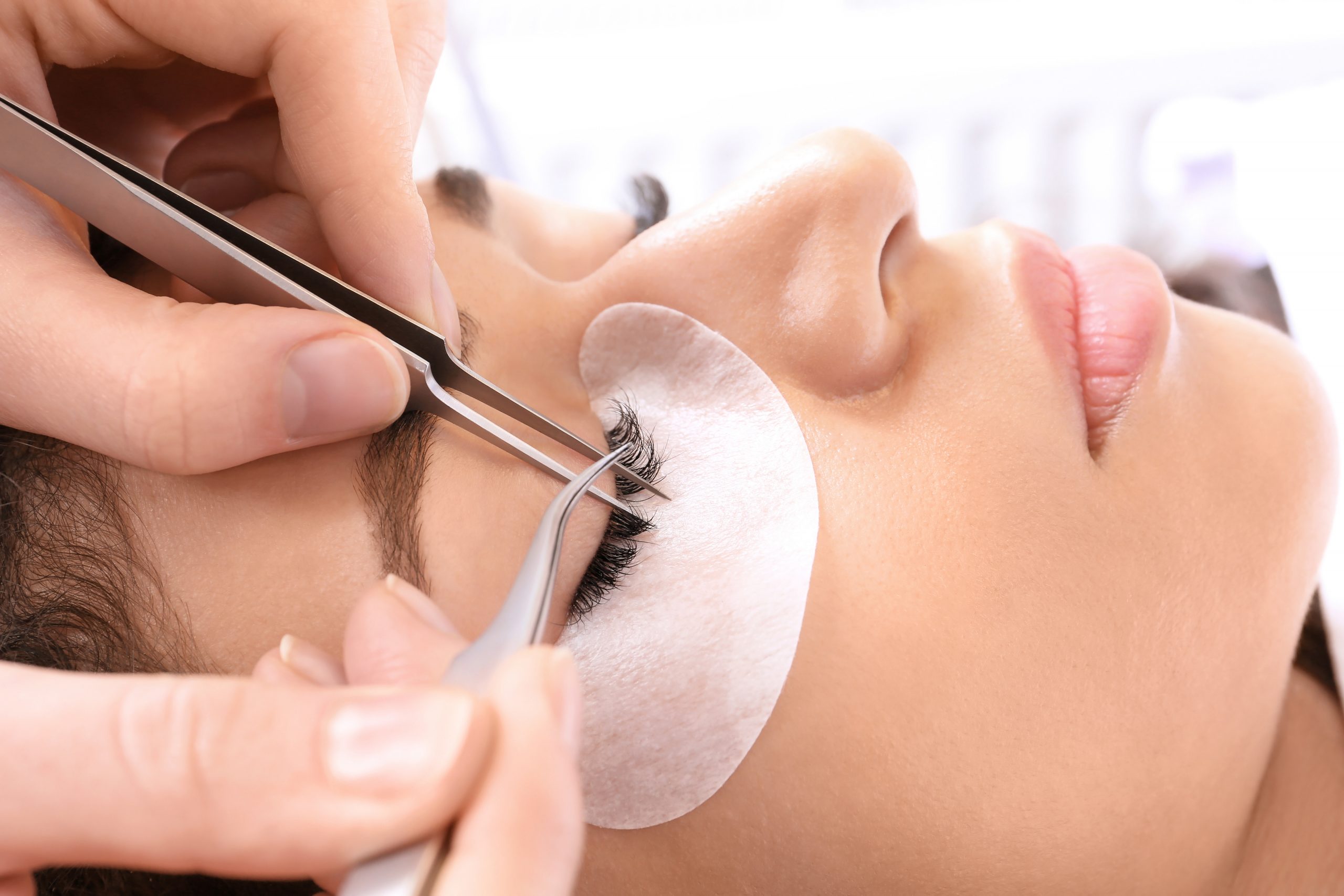 Young woman undergoing eyelash extensions procedure, closeup