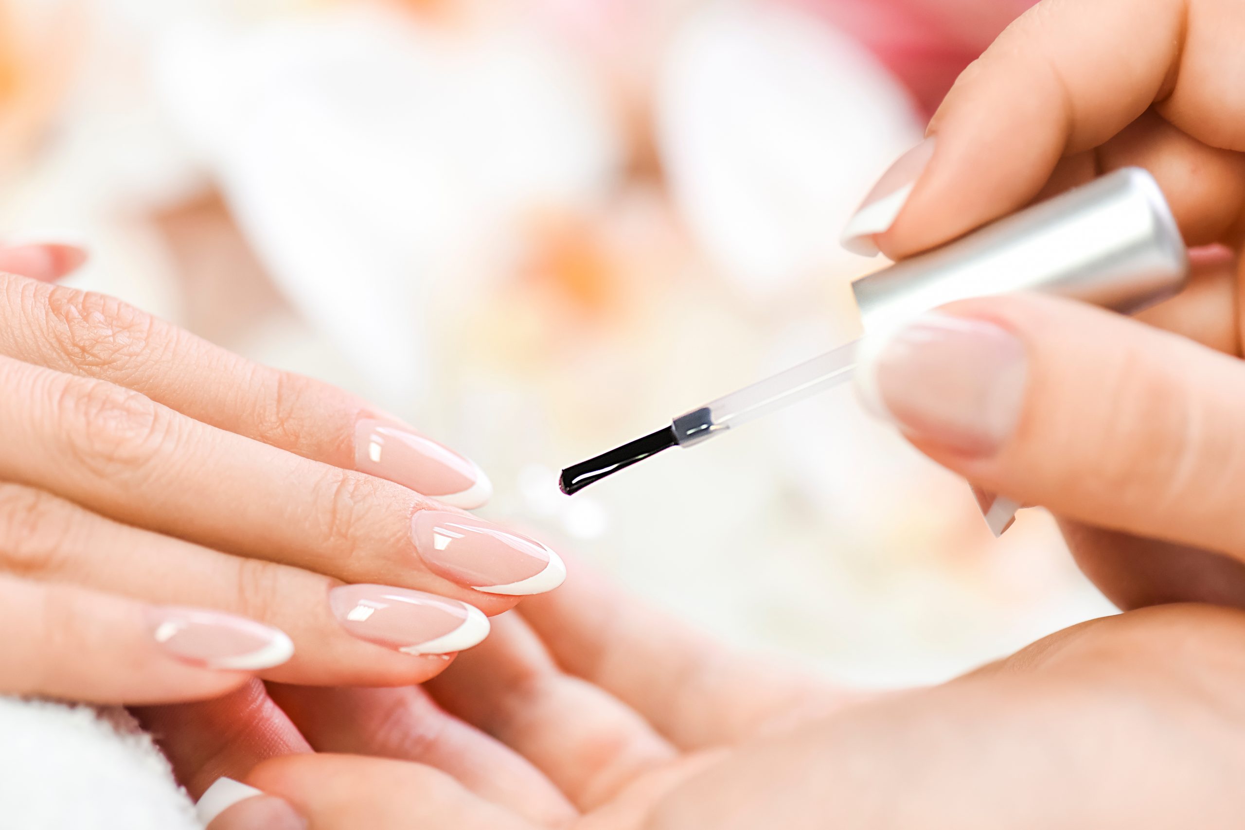 Beautician in luxury salon applying lacquer or varnish gel on nails.Manicure nail paint with brush or artist polish modelation technique.