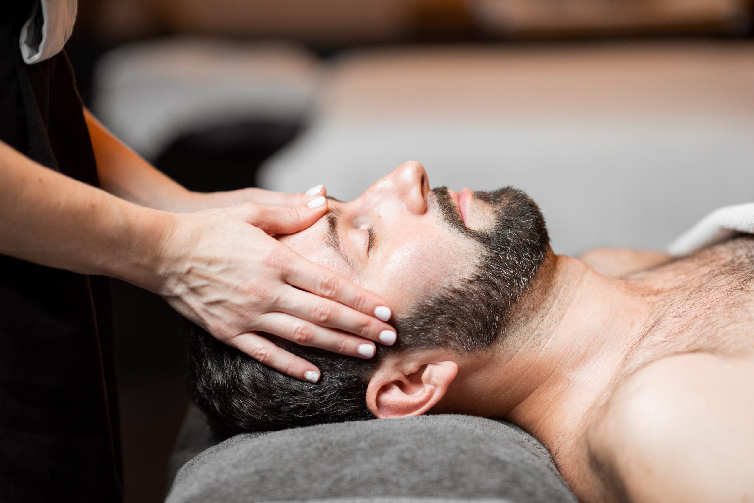 Bearded man receiving a facial massage, relaxing at Spa salon, close-up