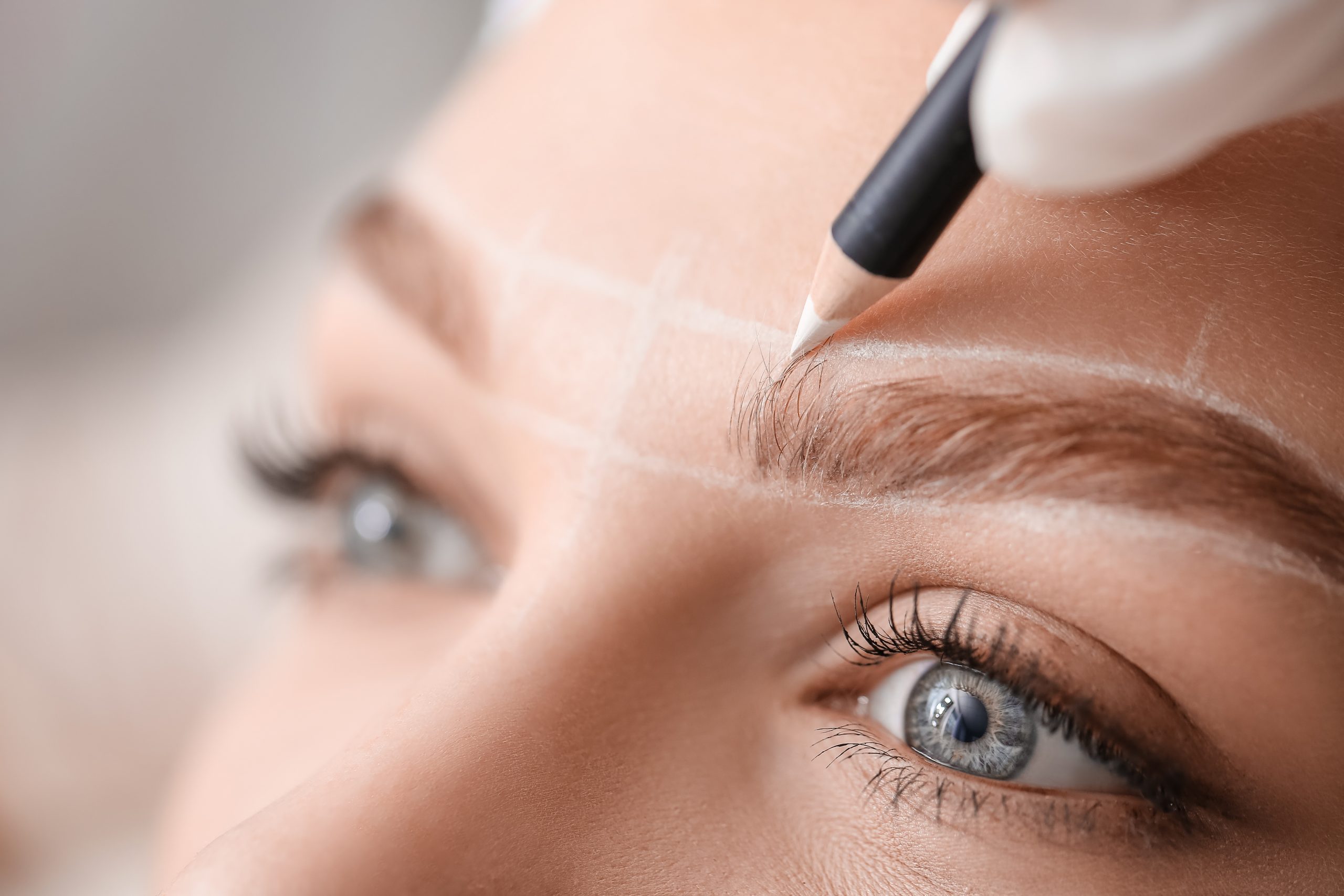 Young woman undergoing eyebrow correction procedure in beauty salon, closeup