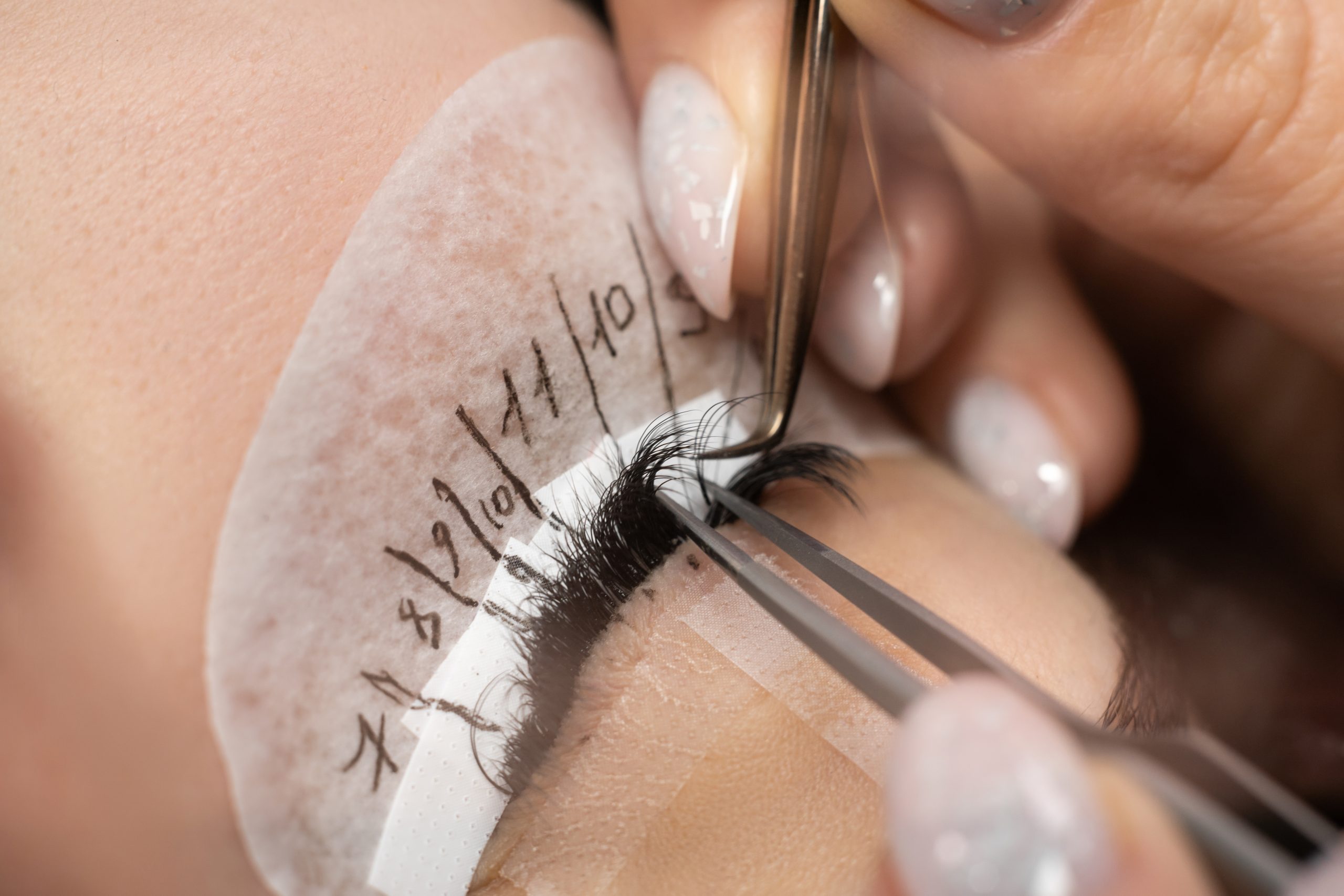 eyelash extension procedure in spa salon close-up. The master inserts an artificial eyelash with tweezers.