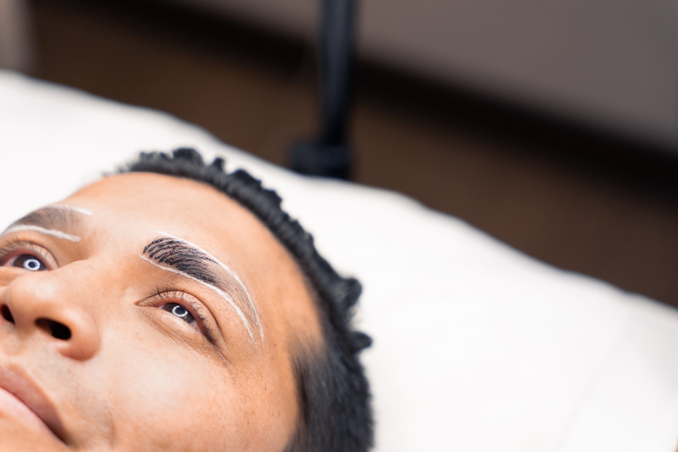 detail of a man during a microblading procedure, one eyebrow with pigment and one with none