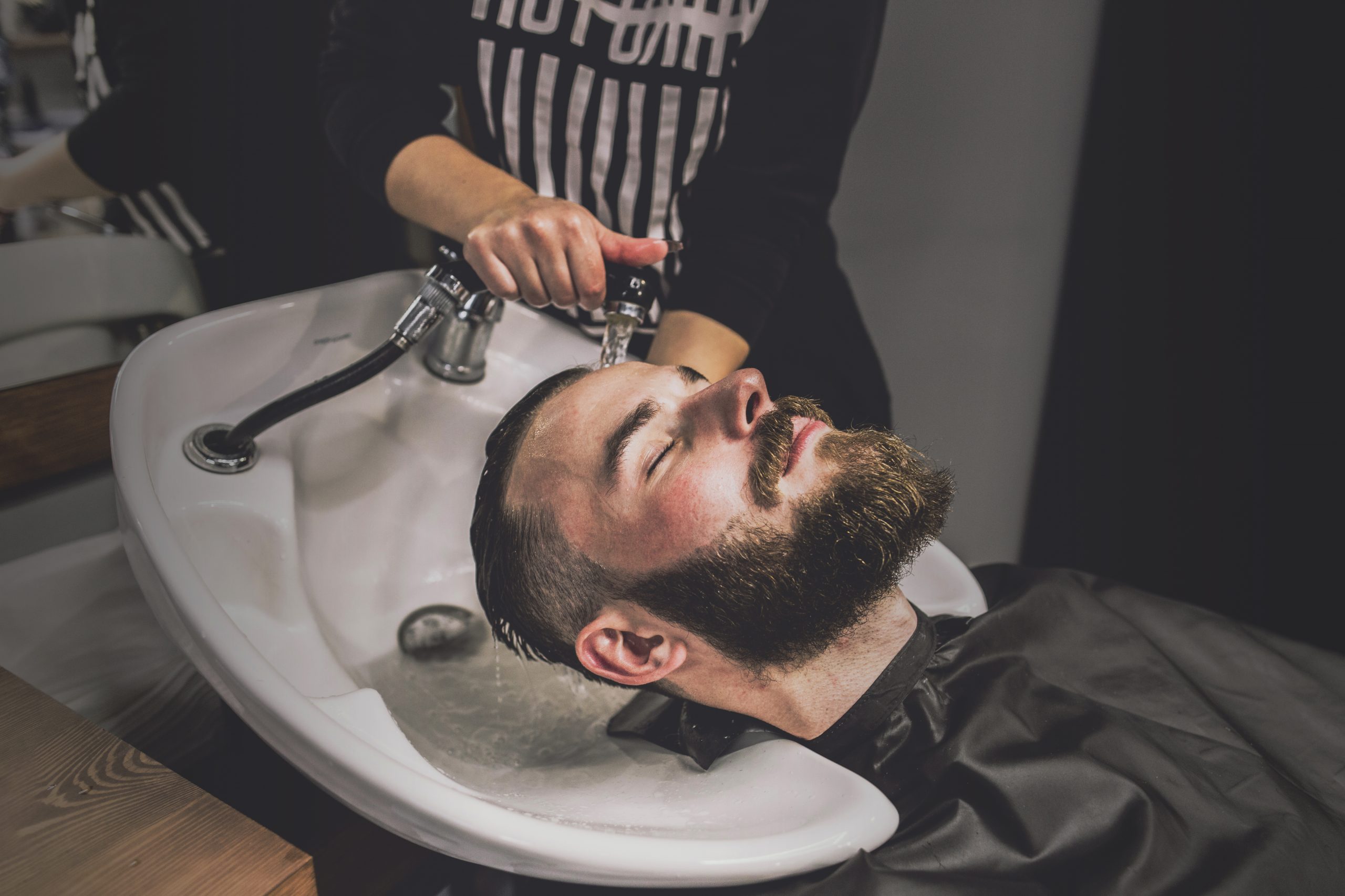 unrecognizable-barber-washing-head-client
