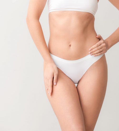 Beautiful young woman in underwear on light background. Concept of plastic surgery