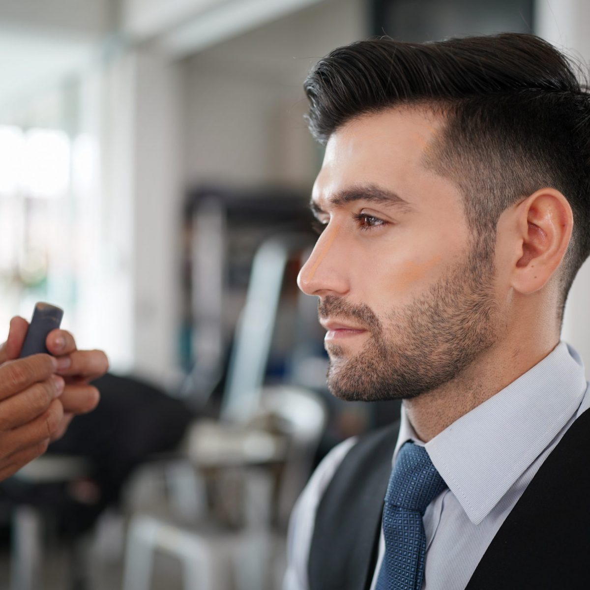 Professional actor preparation before shoot. Handsome young man applying by professional make up of visagist. Male makeup